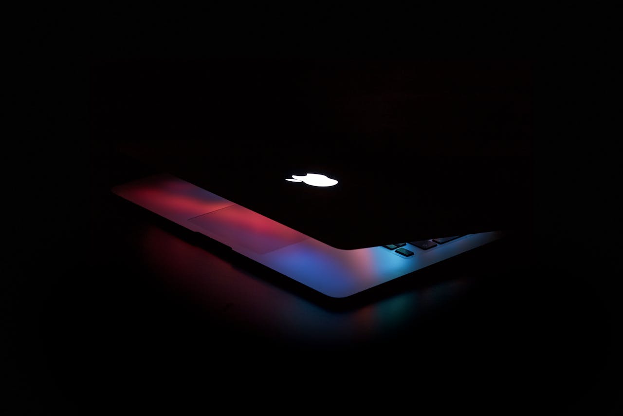 Captivating close-up of a partially open laptop with colorful lighting against a dark background.