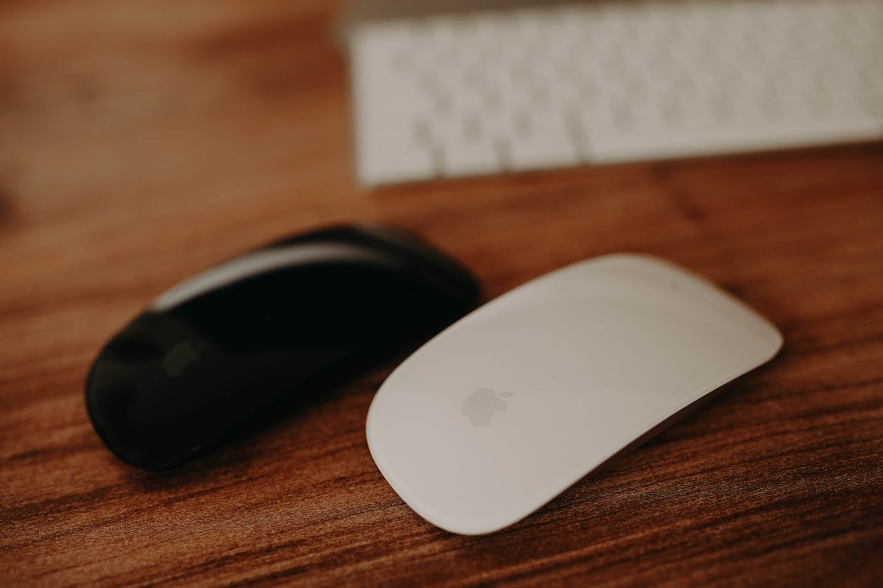 A close-up shot of black and white wireless computer mice on a wooden desk.